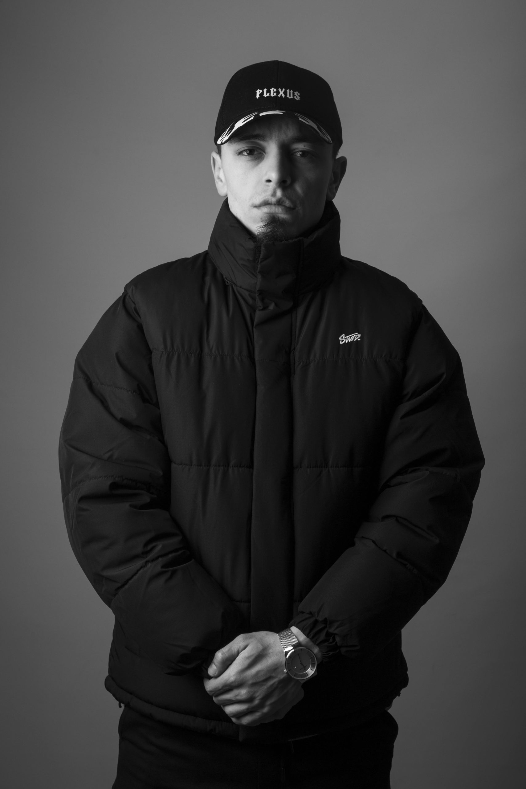 Black and white portrait of a man in a winter coat and hat showcasing fashion style.